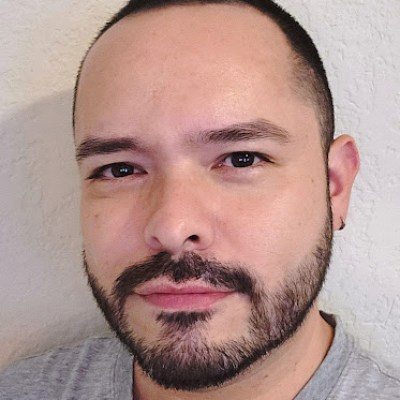 unnamed (59) Person with short hair and beard wearing a gray shirt facing the camera.